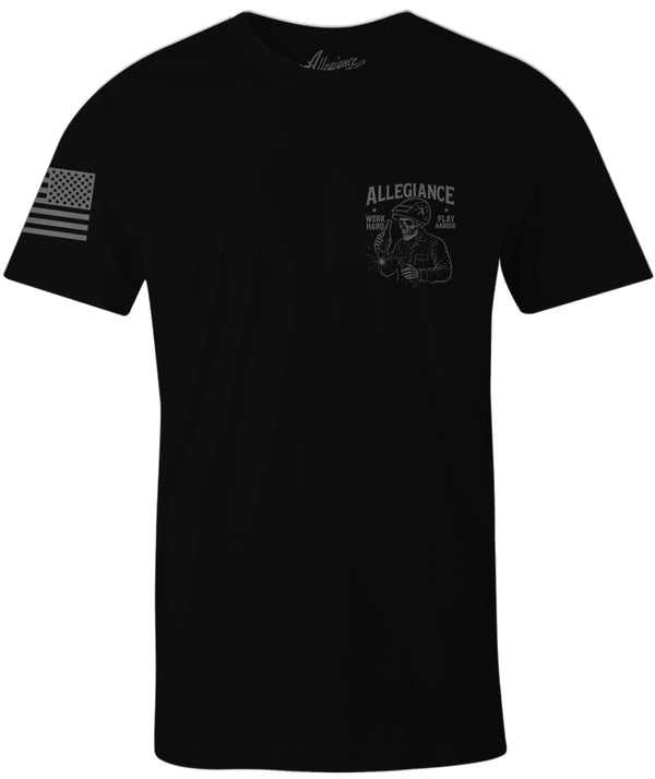 Black Allegiance Play Harder Tee featuring small skeleton welder graphic holding a beer and the phrase Work Hard Play Harder, with an American flag on the sleeve.